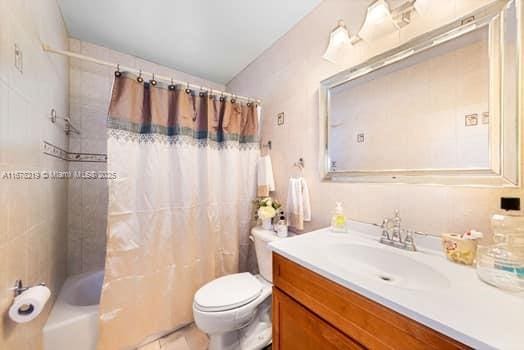 full bathroom featuring vanity, shower / bath combination with curtain, and toilet