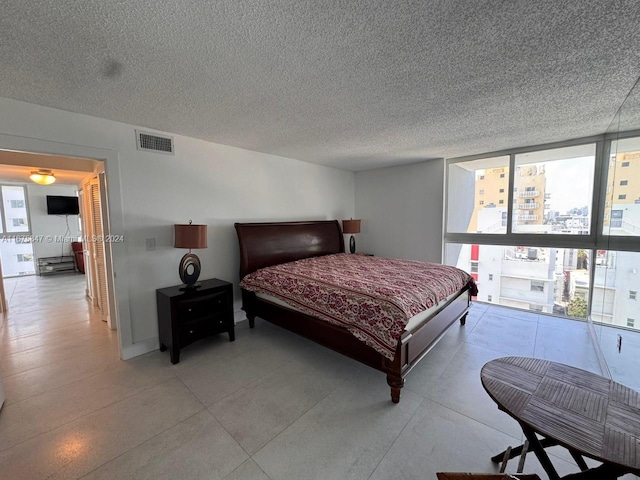 bedroom featuring a textured ceiling and floor to ceiling windows