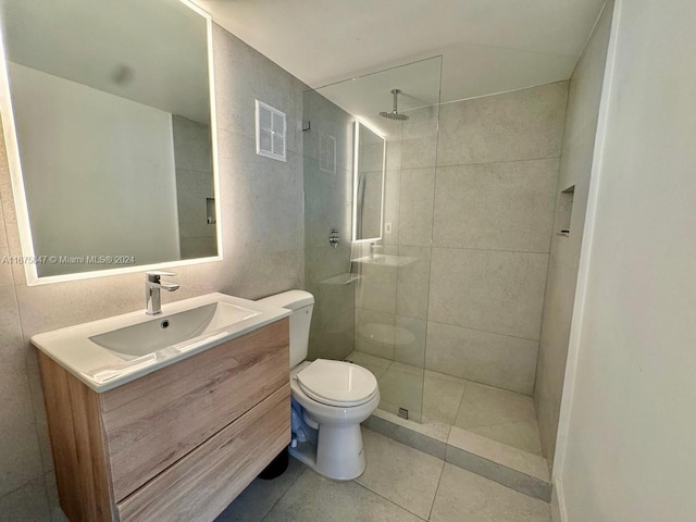 bathroom with vanity, toilet, tile patterned floors, and tiled shower