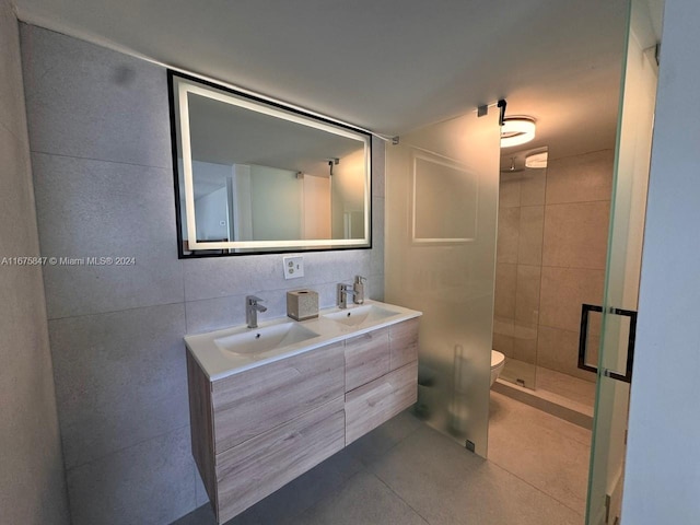 bathroom featuring vanity, toilet, tile walls, and a shower with shower door