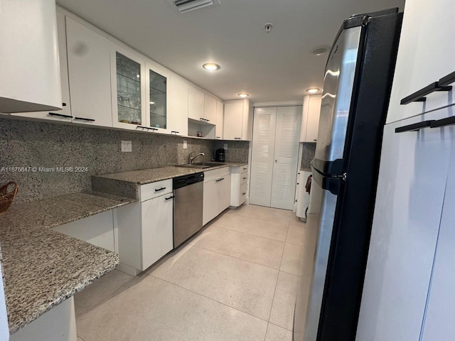 kitchen featuring white cabinets, light stone countertops, dishwasher, refrigerator, and sink