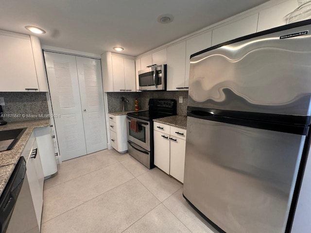 kitchen with white cabinetry, dark stone countertops, appliances with stainless steel finishes, and decorative backsplash