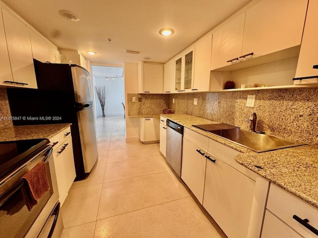 kitchen featuring light stone countertops, sink, white cabinetry, stainless steel appliances, and decorative backsplash