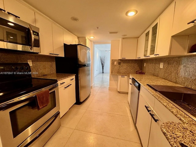 kitchen featuring white cabinets, stainless steel appliances, and light stone counters