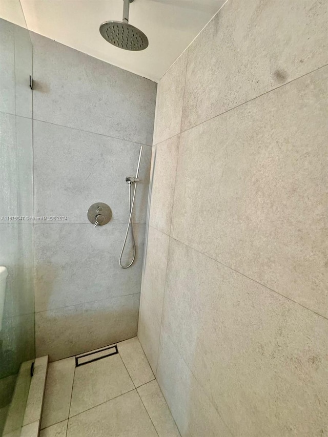 bathroom with a tile shower and tile patterned flooring