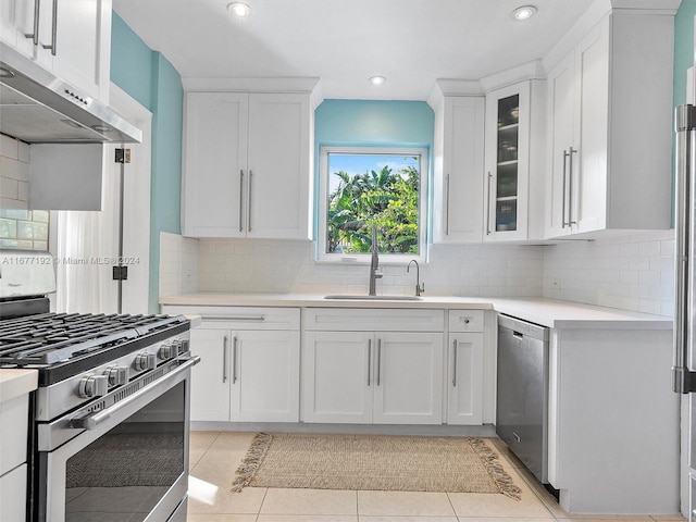 kitchen featuring white cabinets, stainless steel appliances, backsplash, and light tile patterned floors