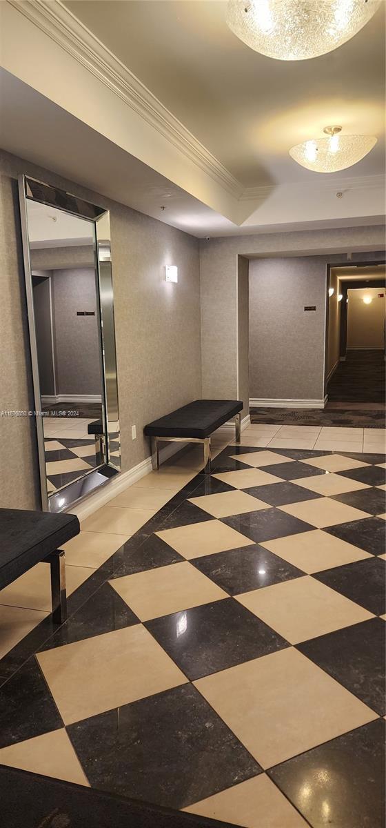 hall with a tray ceiling and ornamental molding