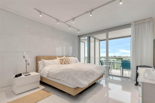 bedroom with access to exterior, a wall of windows, rail lighting, and light tile patterned flooring