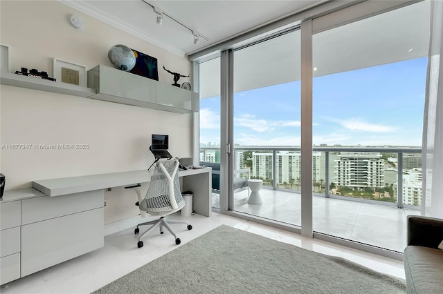 home office with a wall of windows, built in desk, a healthy amount of sunlight, and track lighting