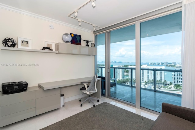 tiled home office featuring ornamental molding, floor to ceiling windows, built in desk, and rail lighting