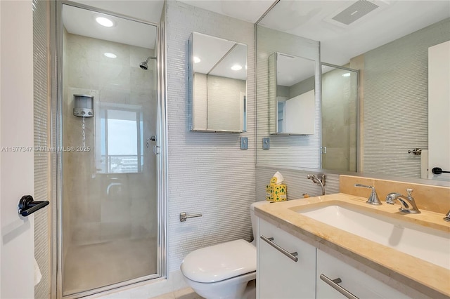 bathroom with toilet, tile walls, vanity, and walk in shower