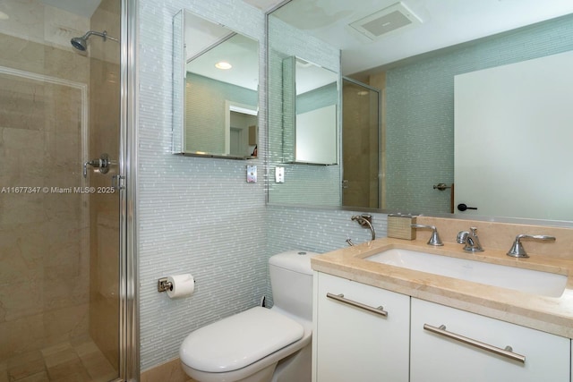 bathroom featuring a shower with door, toilet, tile walls, tasteful backsplash, and vanity