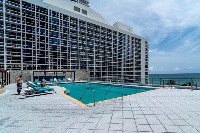 view of swimming pool featuring a patio and a water view