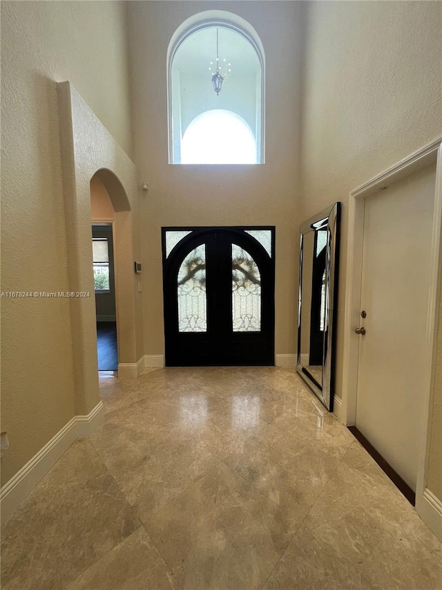 entrance foyer with an inviting chandelier, a healthy amount of sunlight, and a high ceiling