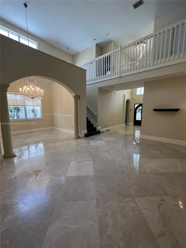 interior space with a notable chandelier, a healthy amount of sunlight, decorative columns, and a high ceiling