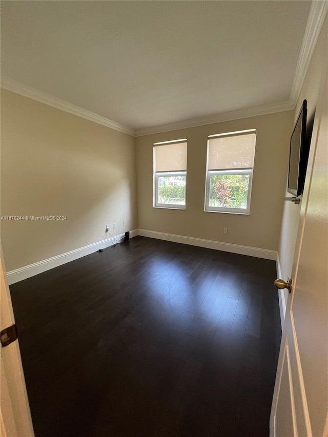 spare room featuring ornamental molding and dark hardwood / wood-style floors