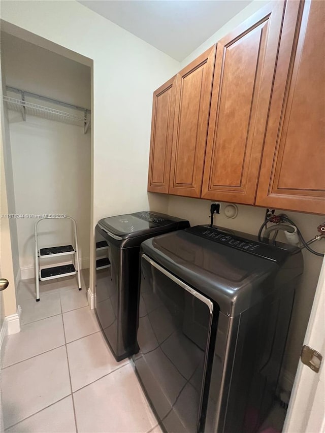 laundry room with washer and dryer, light tile patterned flooring, and cabinets