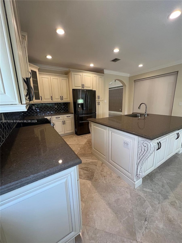 kitchen with sink, white cabinetry, dark stone counters, and black fridge