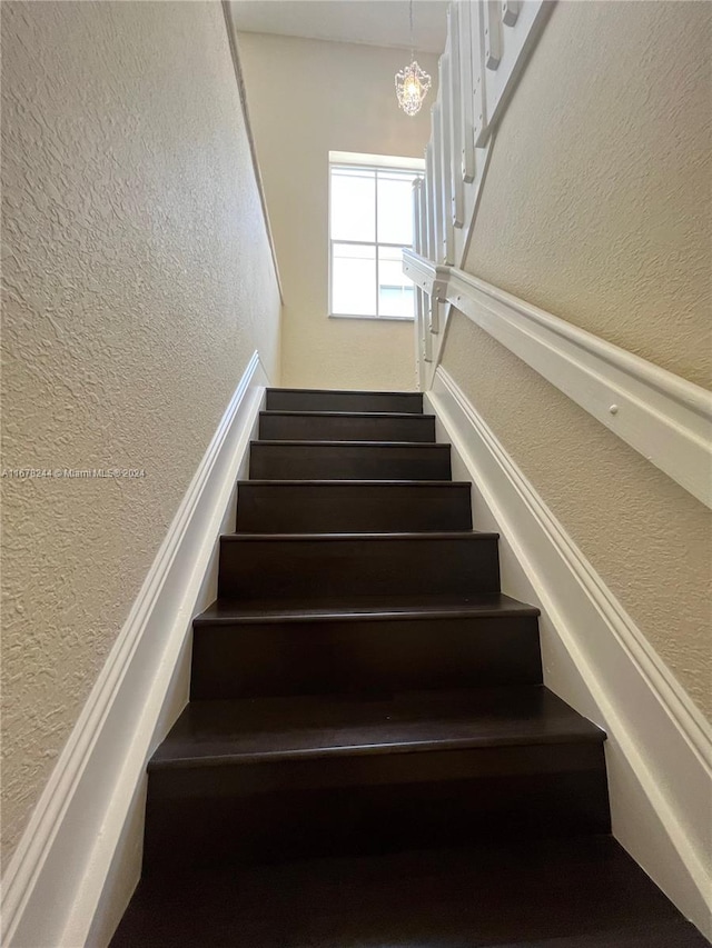 stairs with a notable chandelier