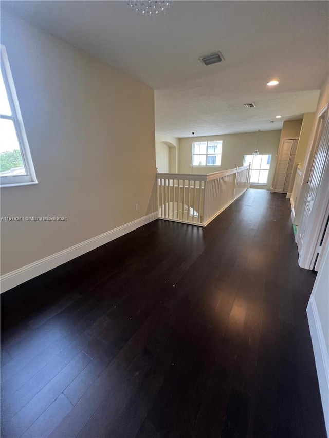 spare room featuring a notable chandelier and dark hardwood / wood-style floors