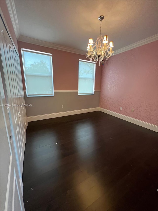 unfurnished room featuring ornamental molding, a chandelier, and dark wood-type flooring