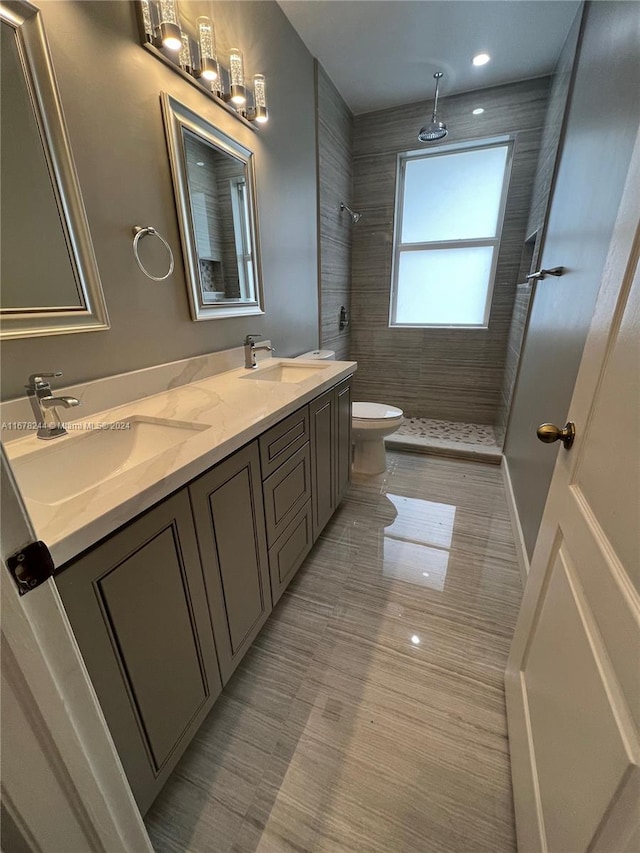 bathroom with vanity, a tile shower, and toilet