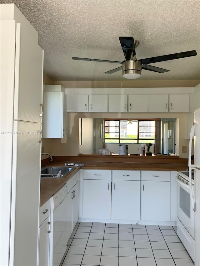 kitchen featuring sink, white cabinets, a textured ceiling, and white appliances