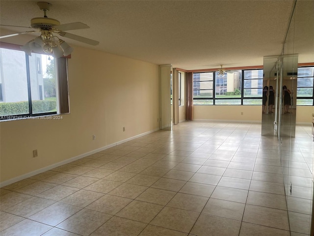 tiled empty room with a textured ceiling and ceiling fan