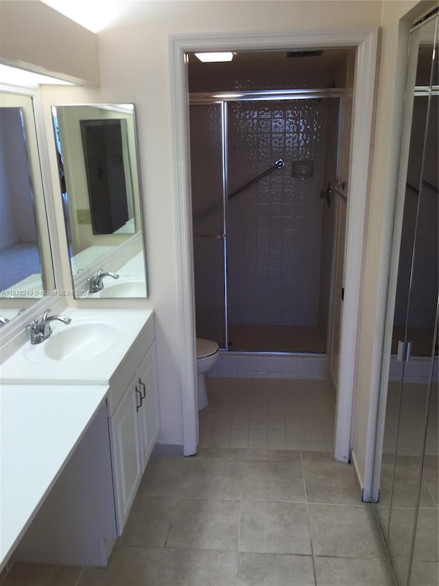 bathroom featuring vanity, tile patterned flooring, toilet, and an enclosed shower