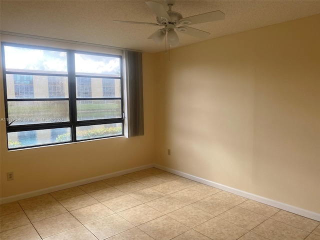 empty room with ceiling fan, a textured ceiling, and light tile patterned flooring