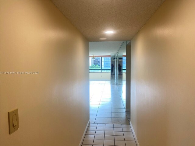 corridor featuring a textured ceiling and light tile patterned flooring