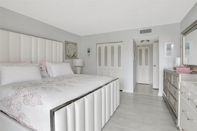 bedroom with a closet, light hardwood / wood-style floors, and a textured ceiling