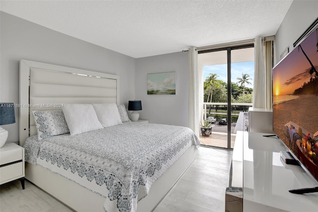 bedroom featuring light hardwood / wood-style flooring, access to outside, and a textured ceiling