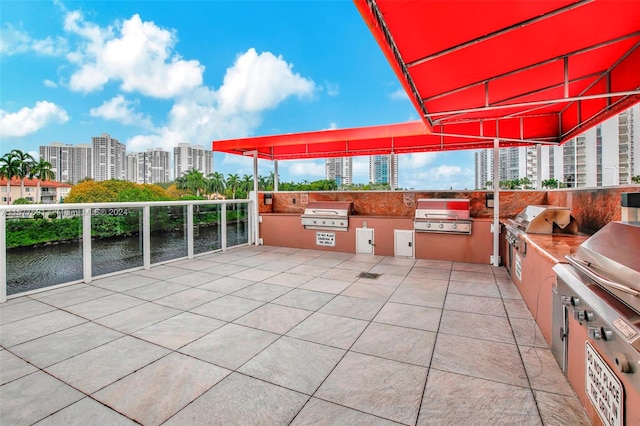 view of patio / terrace featuring area for grilling, a water view, and a grill