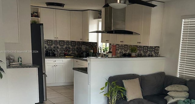 kitchen featuring light tile patterned flooring, island range hood, backsplash, white cabinetry, and stainless steel refrigerator