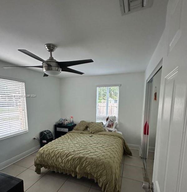 tiled bedroom featuring a closet, ceiling fan, and multiple windows