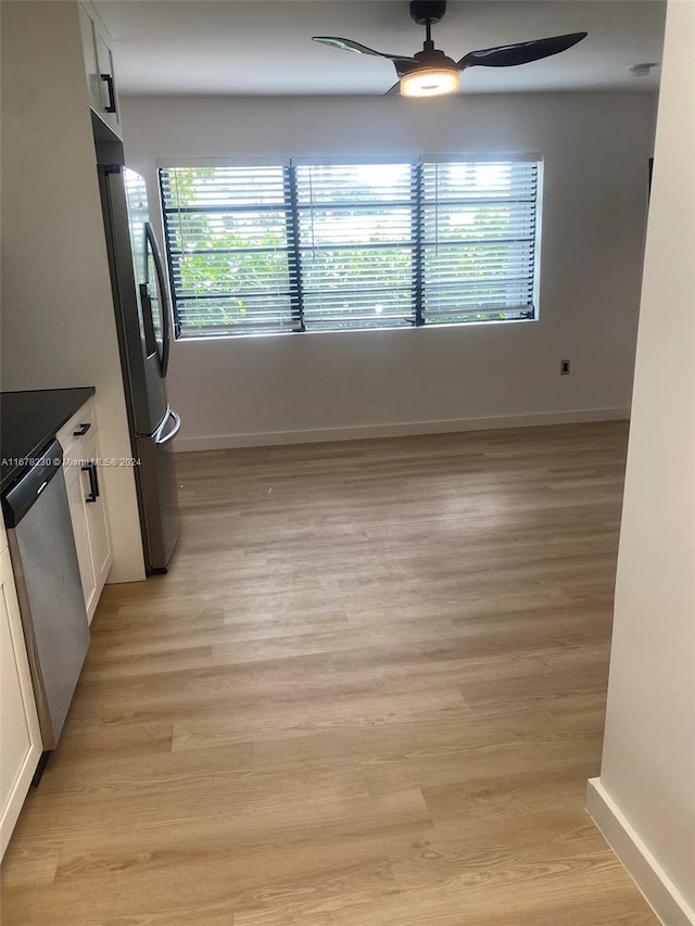 kitchen with appliances with stainless steel finishes, white cabinets, ceiling fan, and light hardwood / wood-style floors