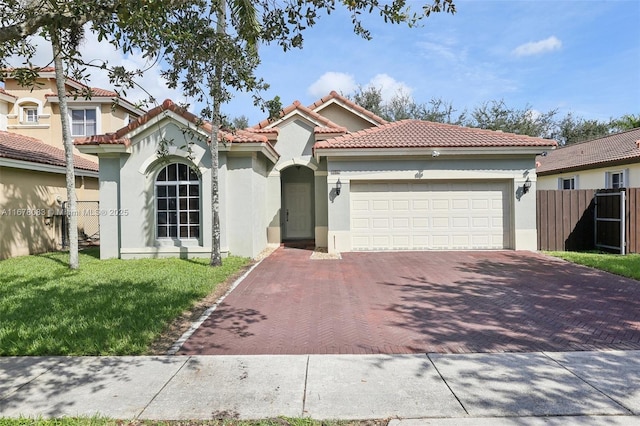 mediterranean / spanish home with stucco siding, a front lawn, a tile roof, decorative driveway, and fence