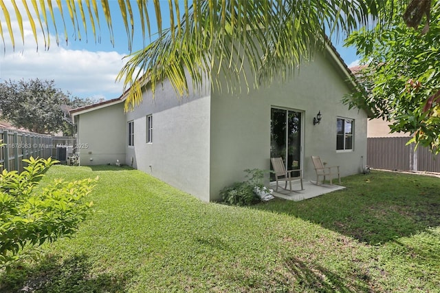 back of house with a lawn, a fenced backyard, and stucco siding