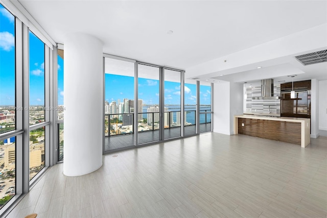 unfurnished living room with a wealth of natural light, expansive windows, and light hardwood / wood-style floors