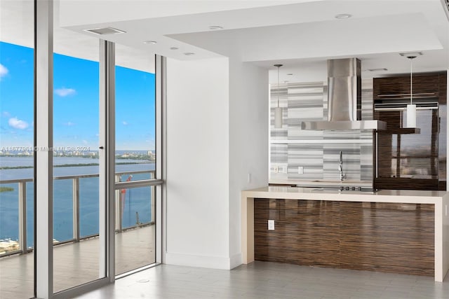 kitchen with floor to ceiling windows, a healthy amount of sunlight, ventilation hood, and a water view