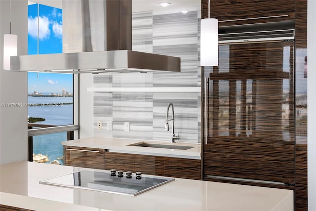 kitchen with island exhaust hood, electric stovetop, sink, pendant lighting, and a water view