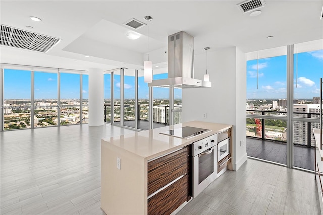 kitchen with island range hood, hanging light fixtures, a healthy amount of sunlight, and black electric cooktop