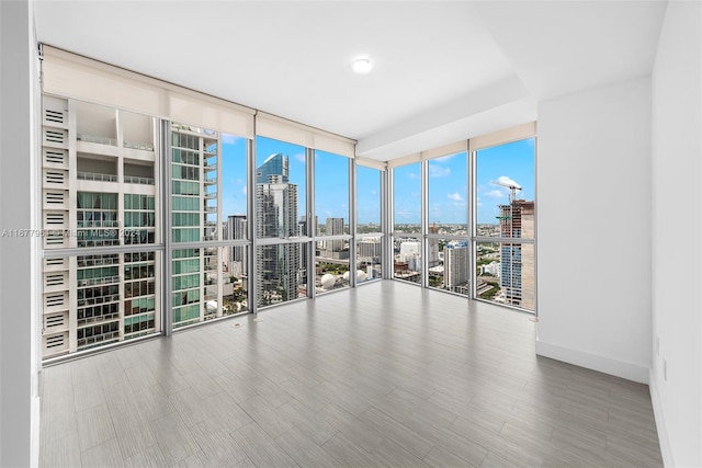 unfurnished room with a healthy amount of sunlight, expansive windows, and wood-type flooring