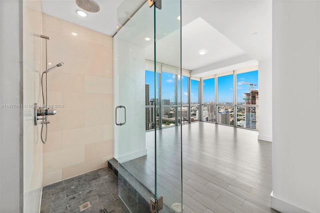 bathroom with expansive windows, hardwood / wood-style flooring, and an enclosed shower