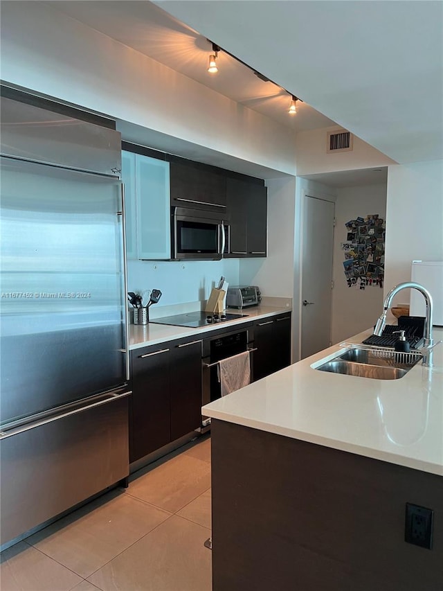 kitchen with dark cabinetry, a sink, appliances with stainless steel finishes, and rail lighting