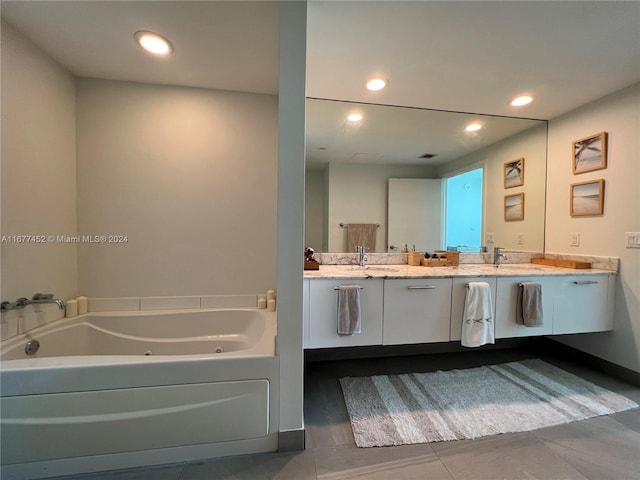 full bathroom featuring double vanity, a tub with jets, baseboards, recessed lighting, and a sink