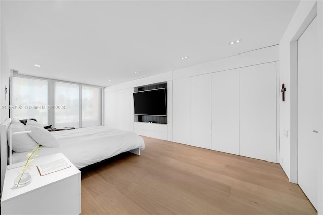 bedroom featuring light wood-type flooring and floor to ceiling windows