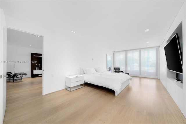 bedroom featuring a wall of windows, access to exterior, and light wood-type flooring