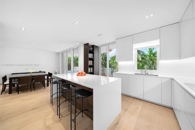 kitchen with a kitchen island, white cabinetry, and light wood-type flooring